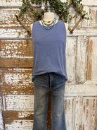 Mannequin wearing a blue sleeveless top and jeans against a rustic wooden background