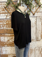 Black top and handmade jewelry worn by a mannequin against an artistic background