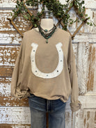 Brown sweatshirt with horseshoe design on a mannequin against a rustic wooden background