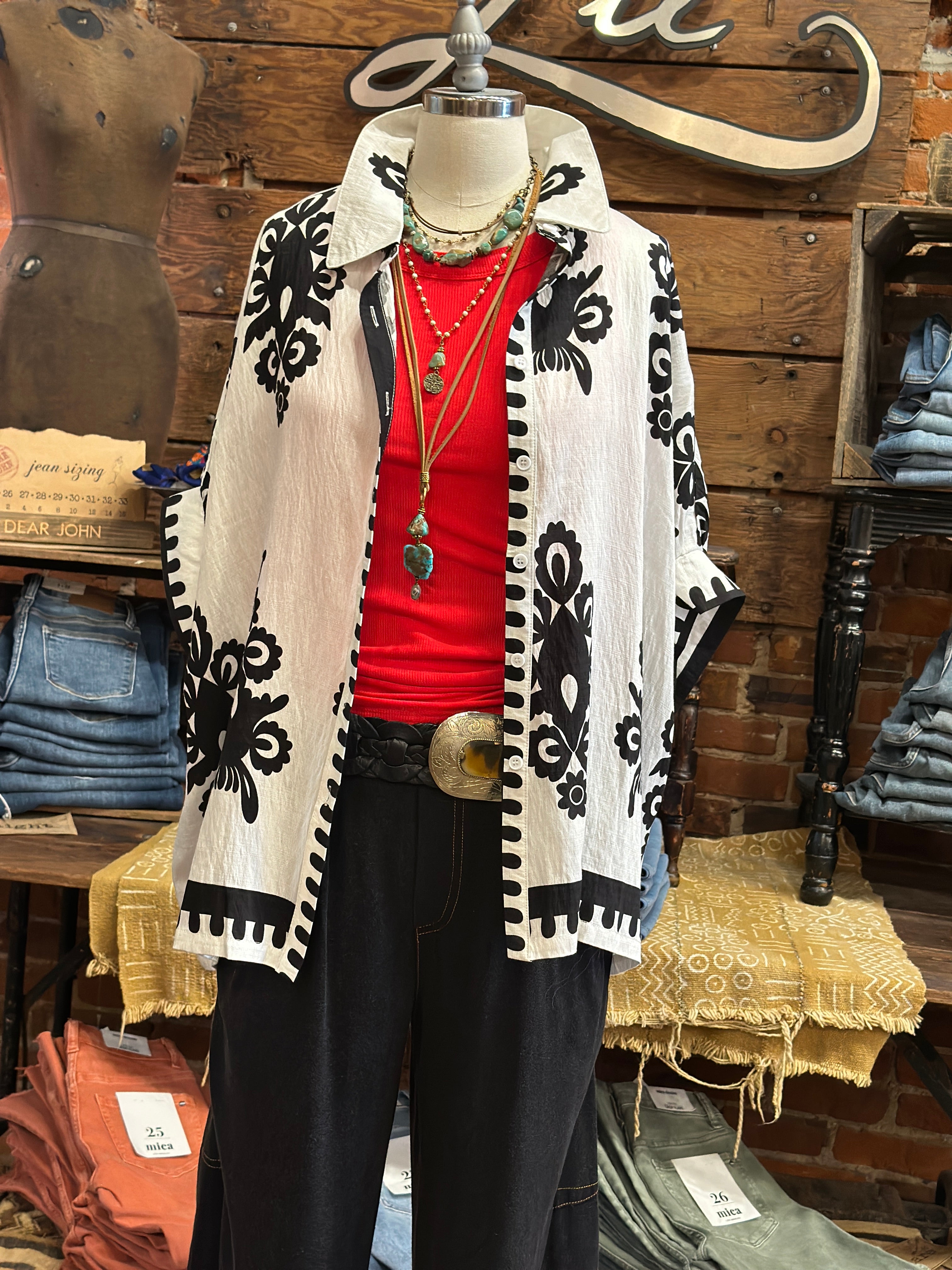 Mannequin wearing a black and white patterned top with a red shirt underneath, in Kansas boutique