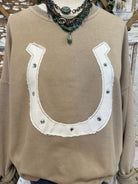 Beige sweatshirt with horseshoe design and artistic turquoise necklace on wooden background
