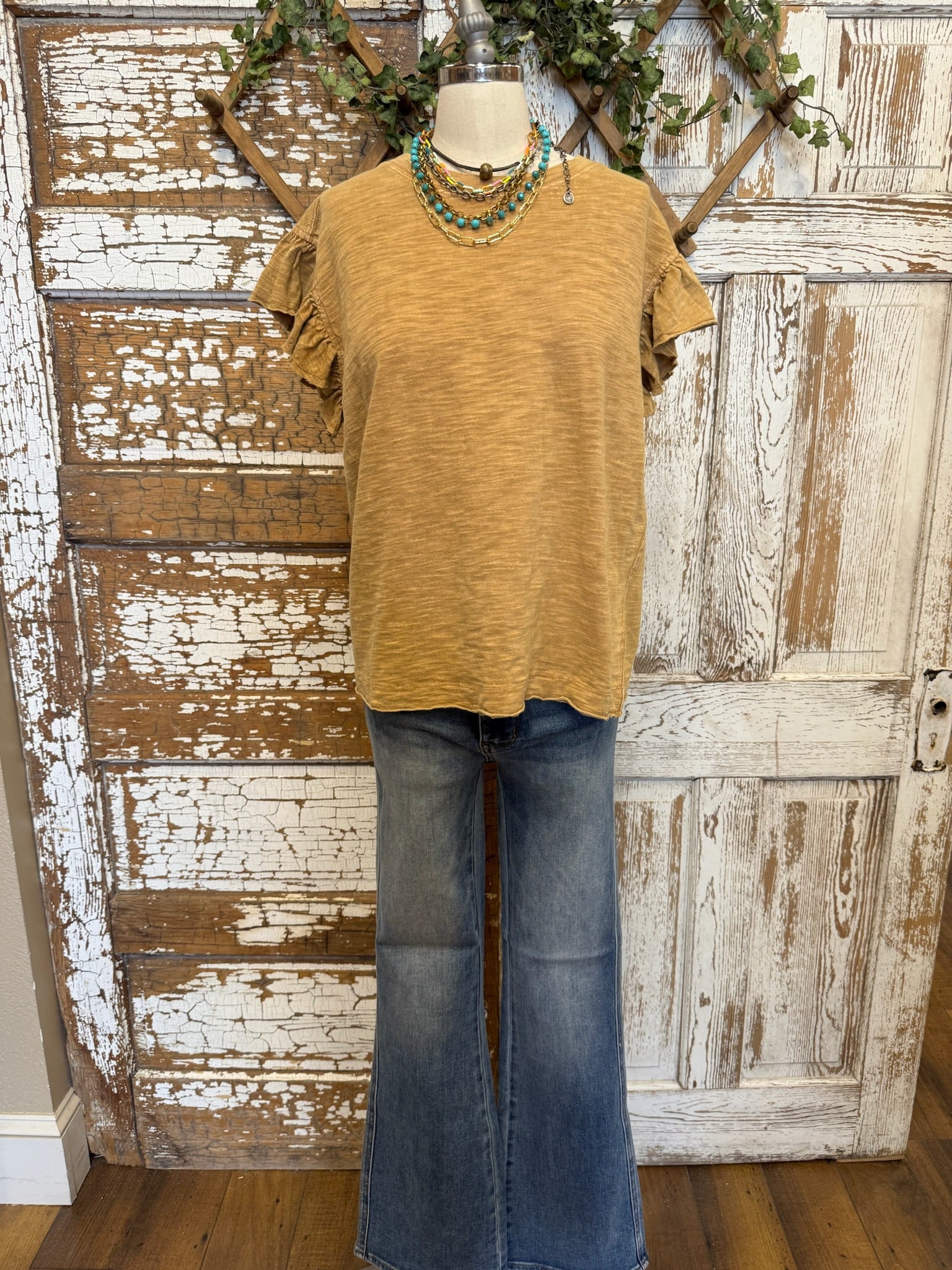 Mannequin wearing a toffee brown shirt and jean pants against an artistic handmade background