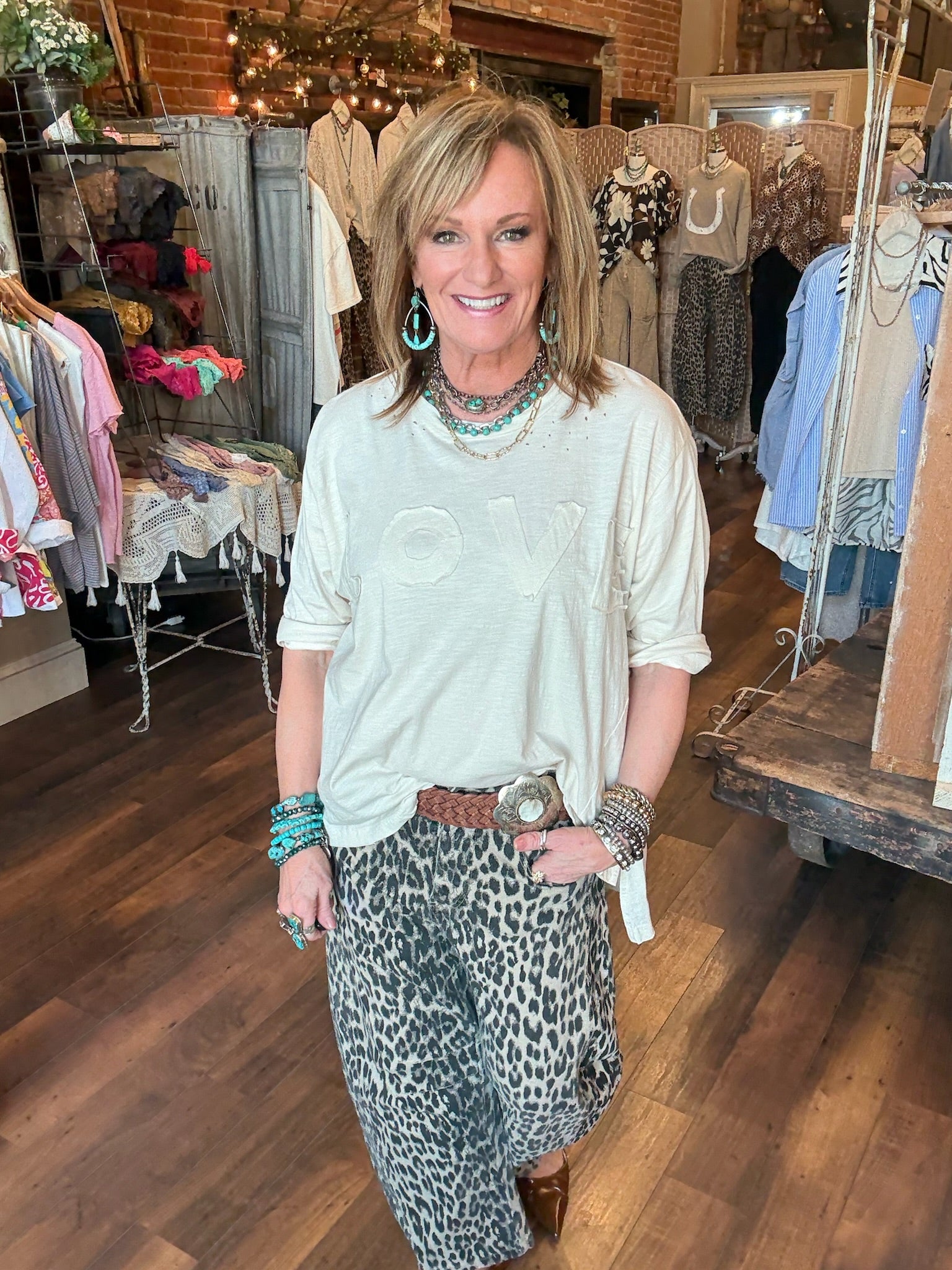 Lu wearing leopard print barrel pants and "LOVE" light weight sweatshirt with turquoise jewelry in Leavenworth, KS boutique