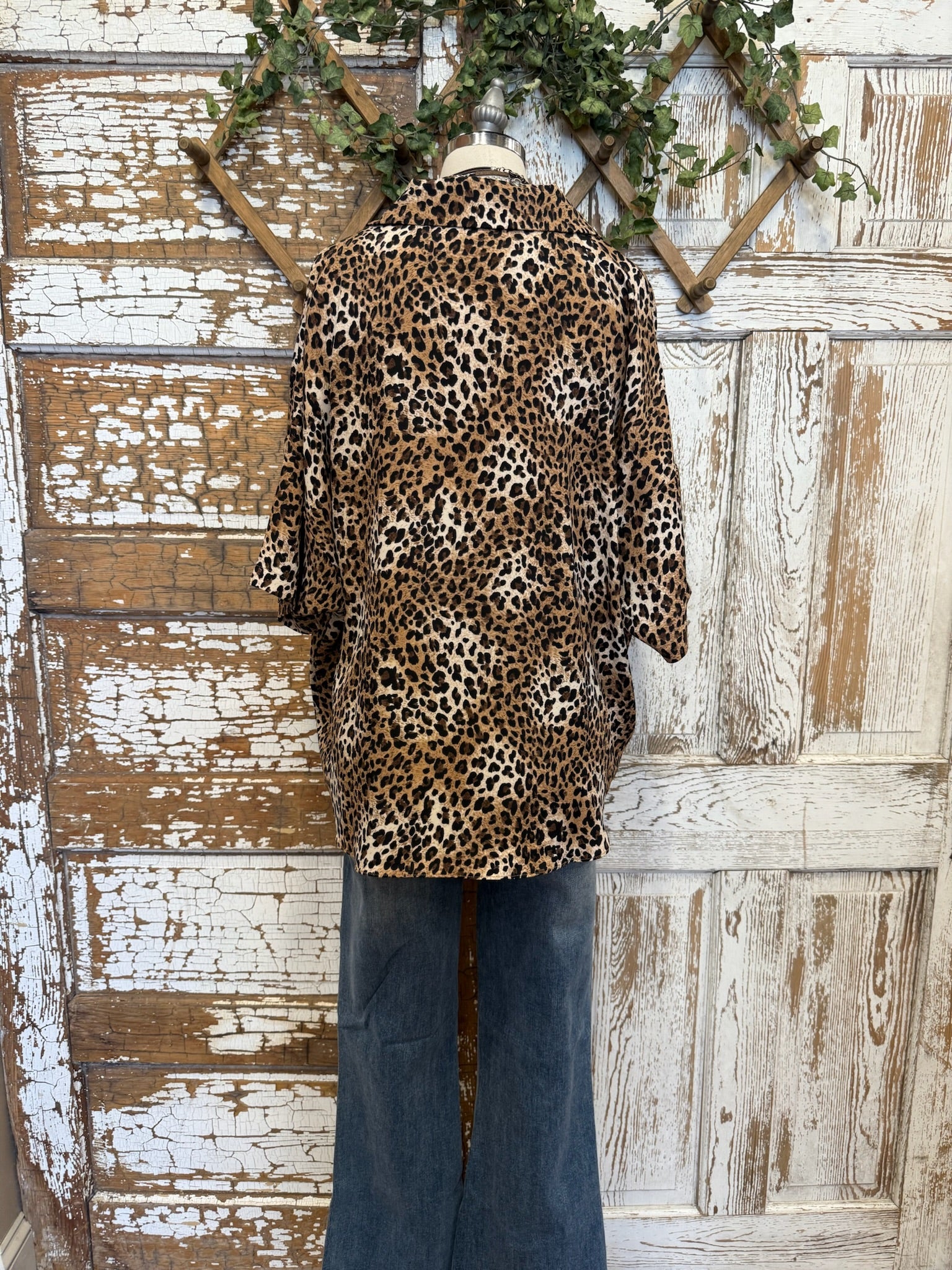 Mannequin wearing a leopard print collared top with handmade turquoise jewelry and blue jeans against a rustic wooden background