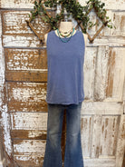 Mannequin wearing a blue sleeveless top and jeans against a rustic wooden background