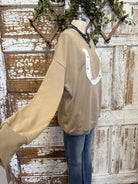 Beige sweatshirt with a white horseshoe design and turquoise handmade necklace on a wooden background