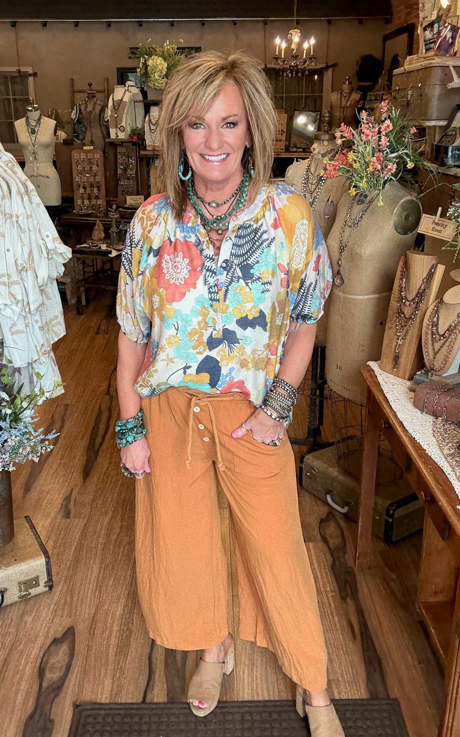 Lu wearing colorful floral blouse with comfortable off-orange pants in Leavenworth, KS boutique