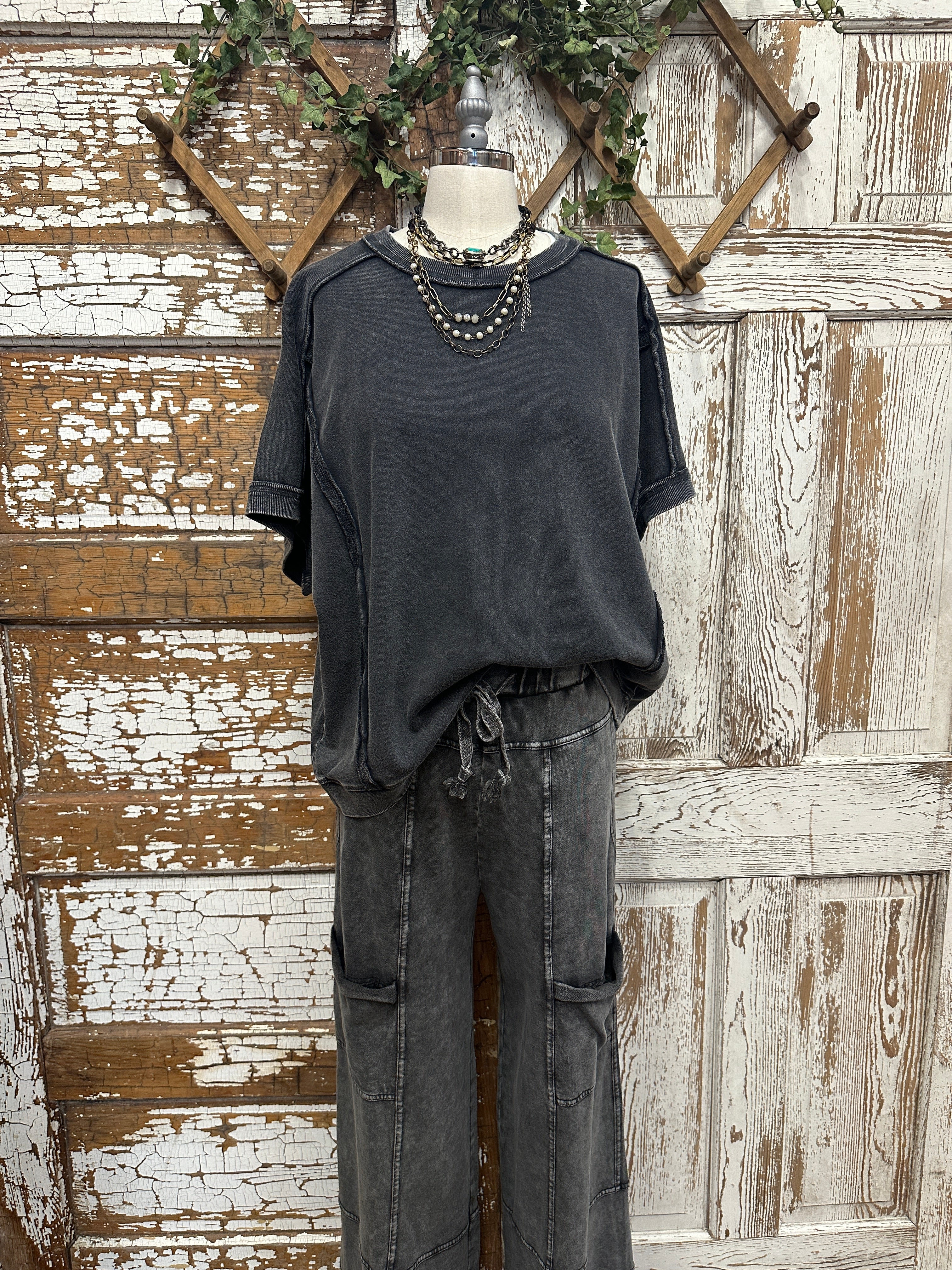 Mannequin wearing grey shirt and boutique clothing pants with handmade jewelry
