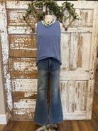 Mannequin wearing a blue sleeveless top and jeans against a rustic wooden door background