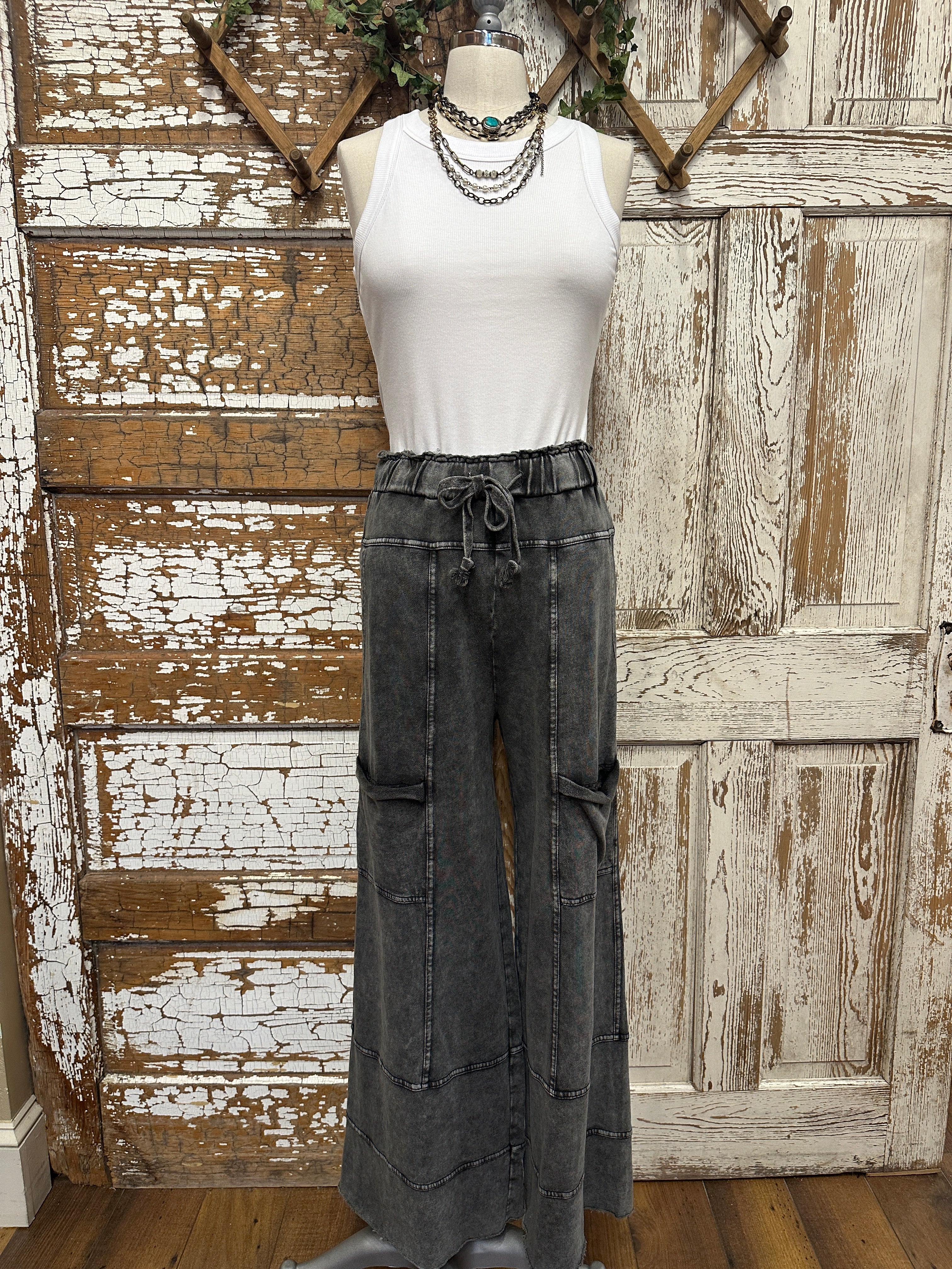 Mannequin wearing a white shirt and leisurewear pants against a rustic wooden background in Springfield, MO boutique with handmade jewelry necklaces