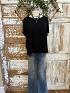 Black top, jeans and handmade jewelry worn by a mannequin against an artistic background
