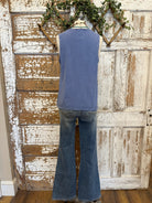 Mannequin wearing a blue sleeveless top and flared jeans against a rustic wooden door background