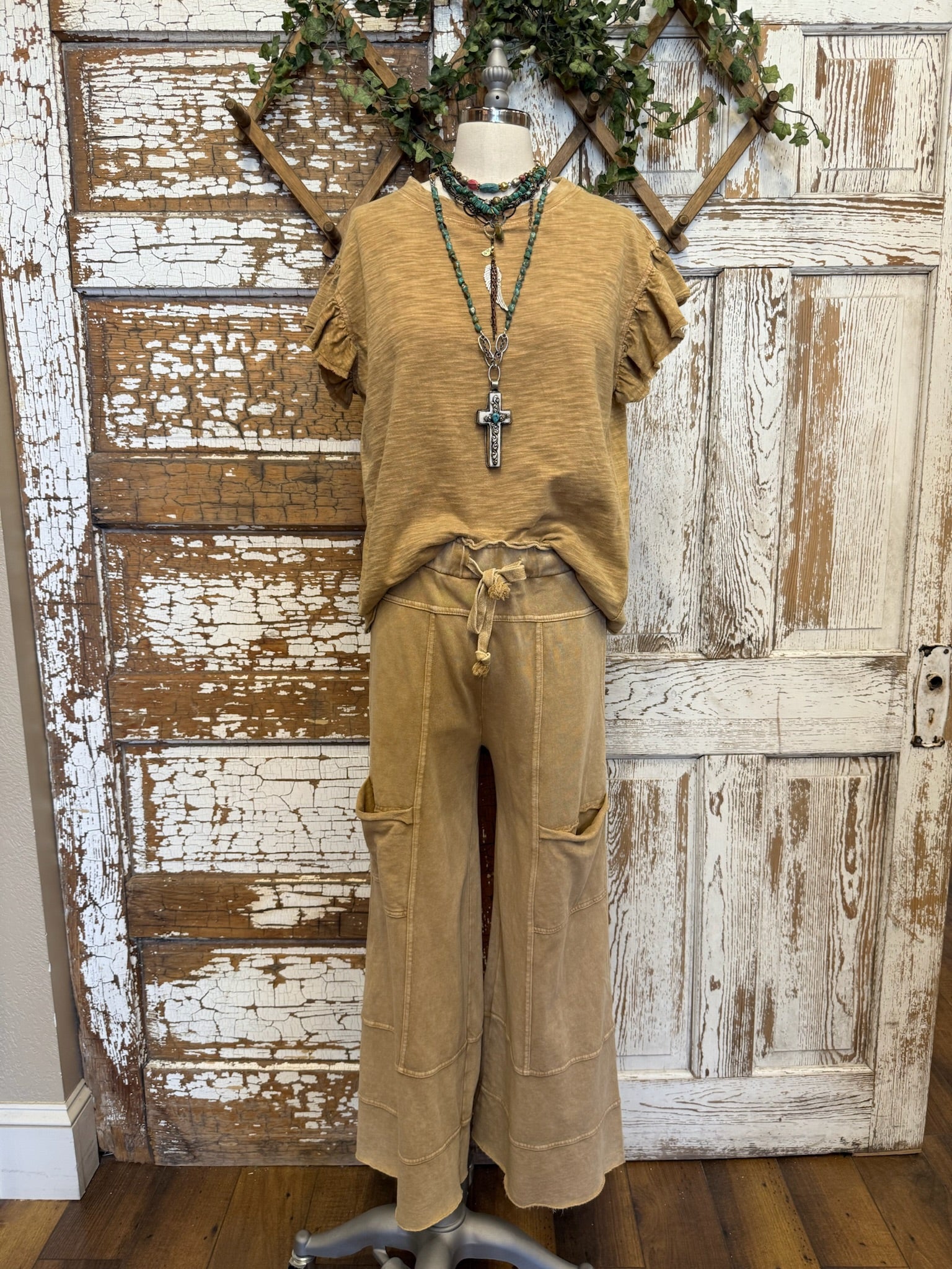 Mannequin wearing a toffee brown shirt and Lu-Leisure stretchy pants against a rustic wooden wall.