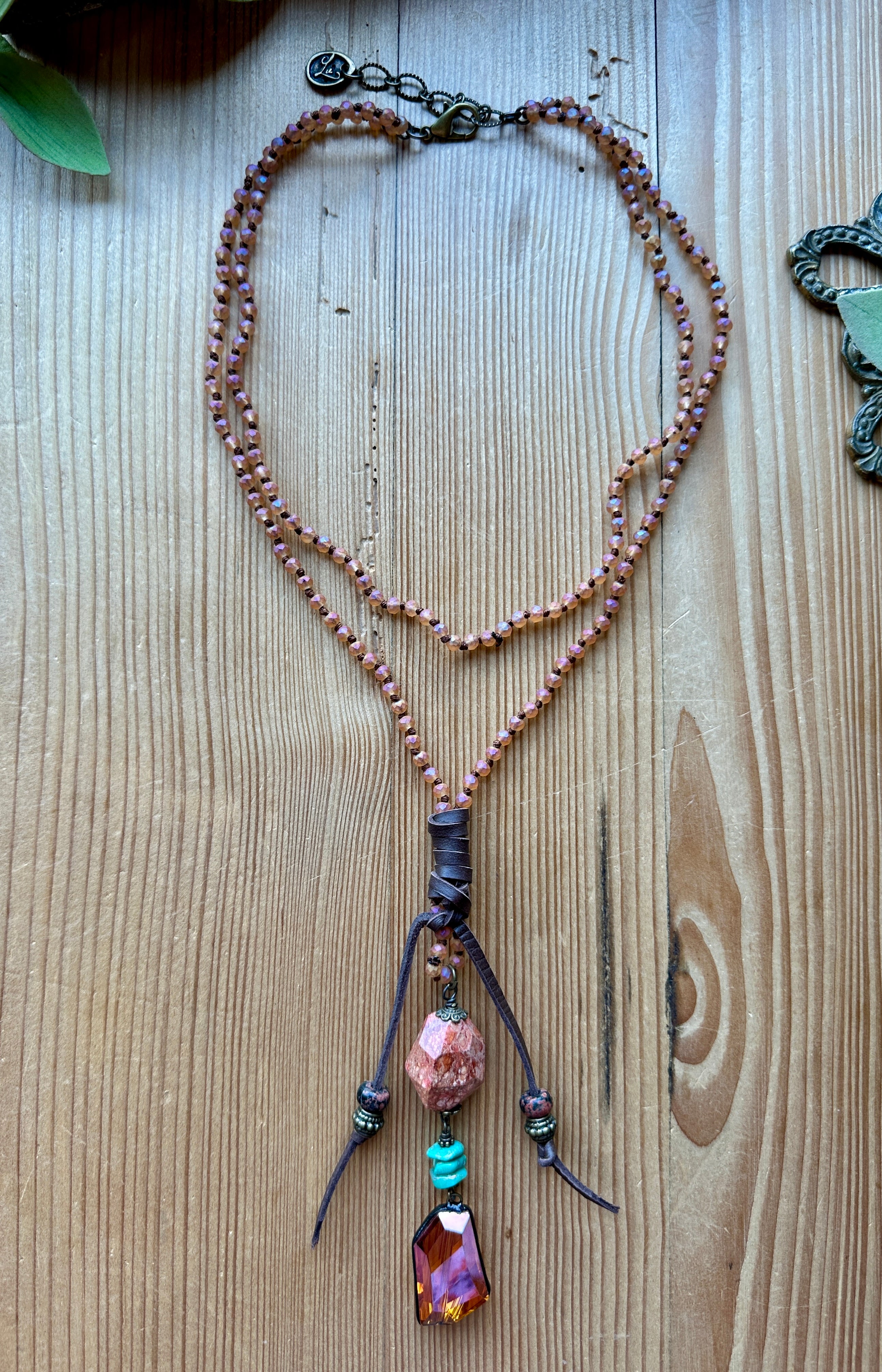 Pink necklace with beads and a pendant on a wooden surface