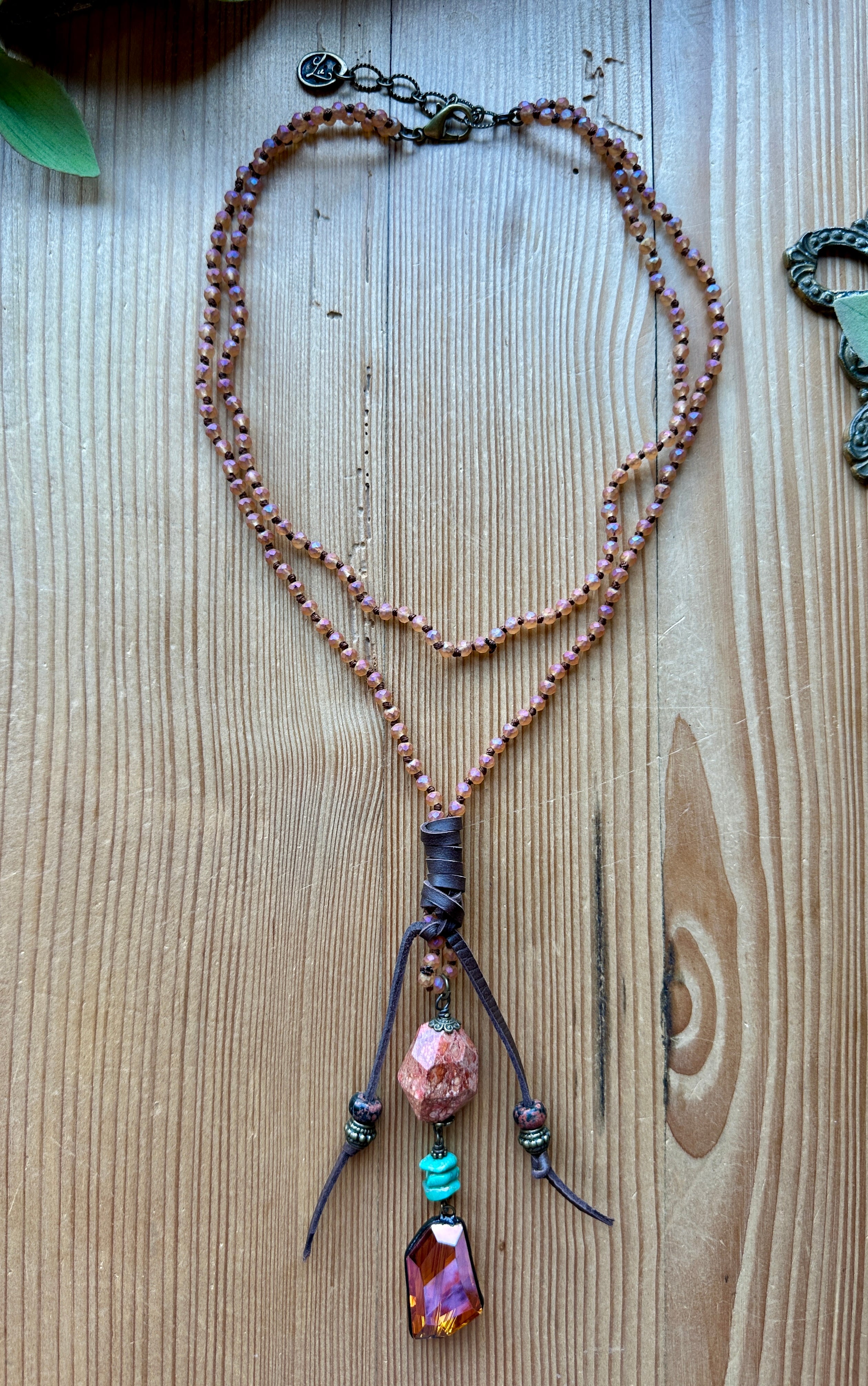 Pink necklace with beads and a pendant on a wooden surface