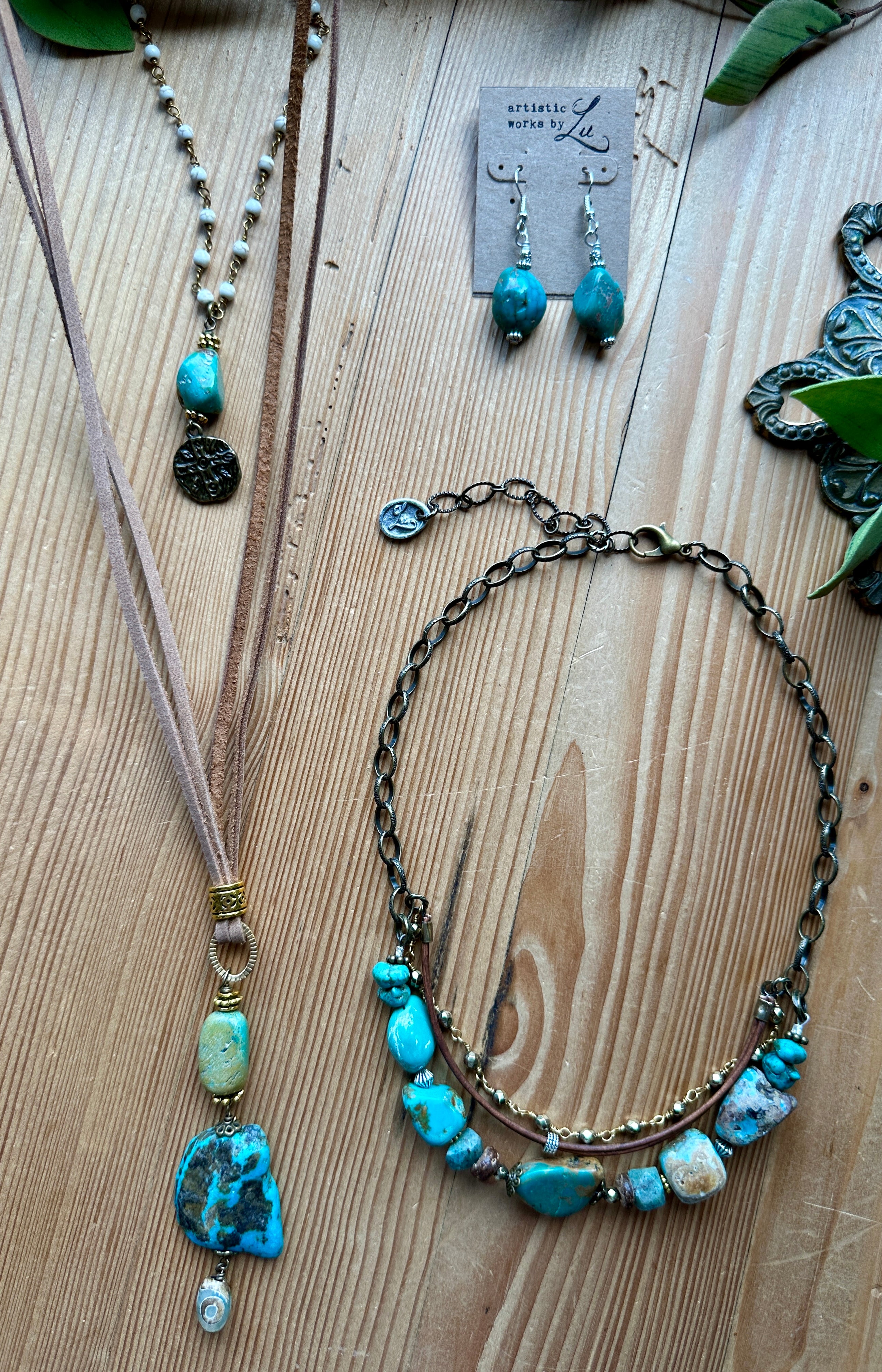 Handmade turquoise jewelry set including necklaces and earrings on a wooden surface