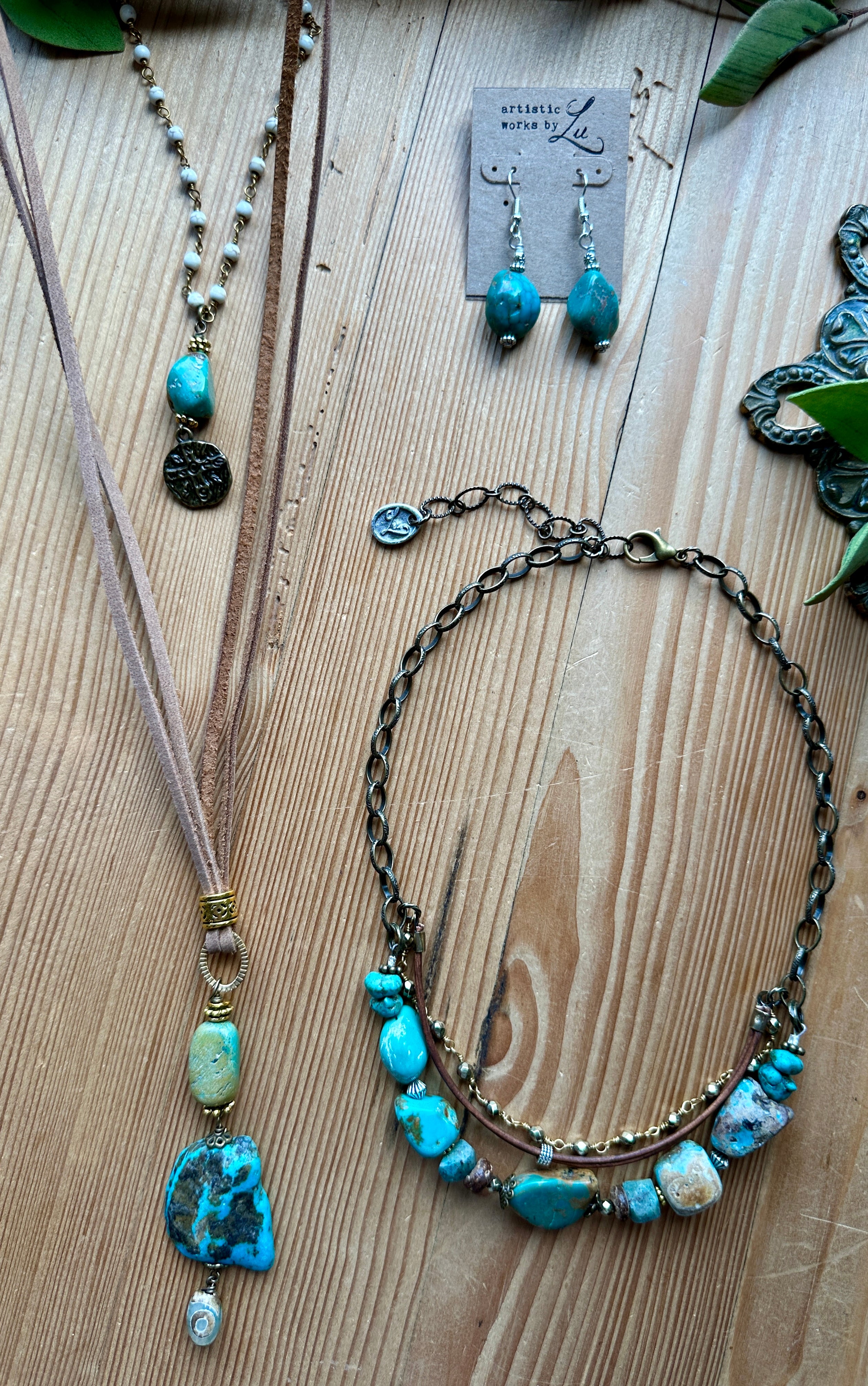 Handmade turquoise jewelry set including necklaces and earrings on a wooden surface