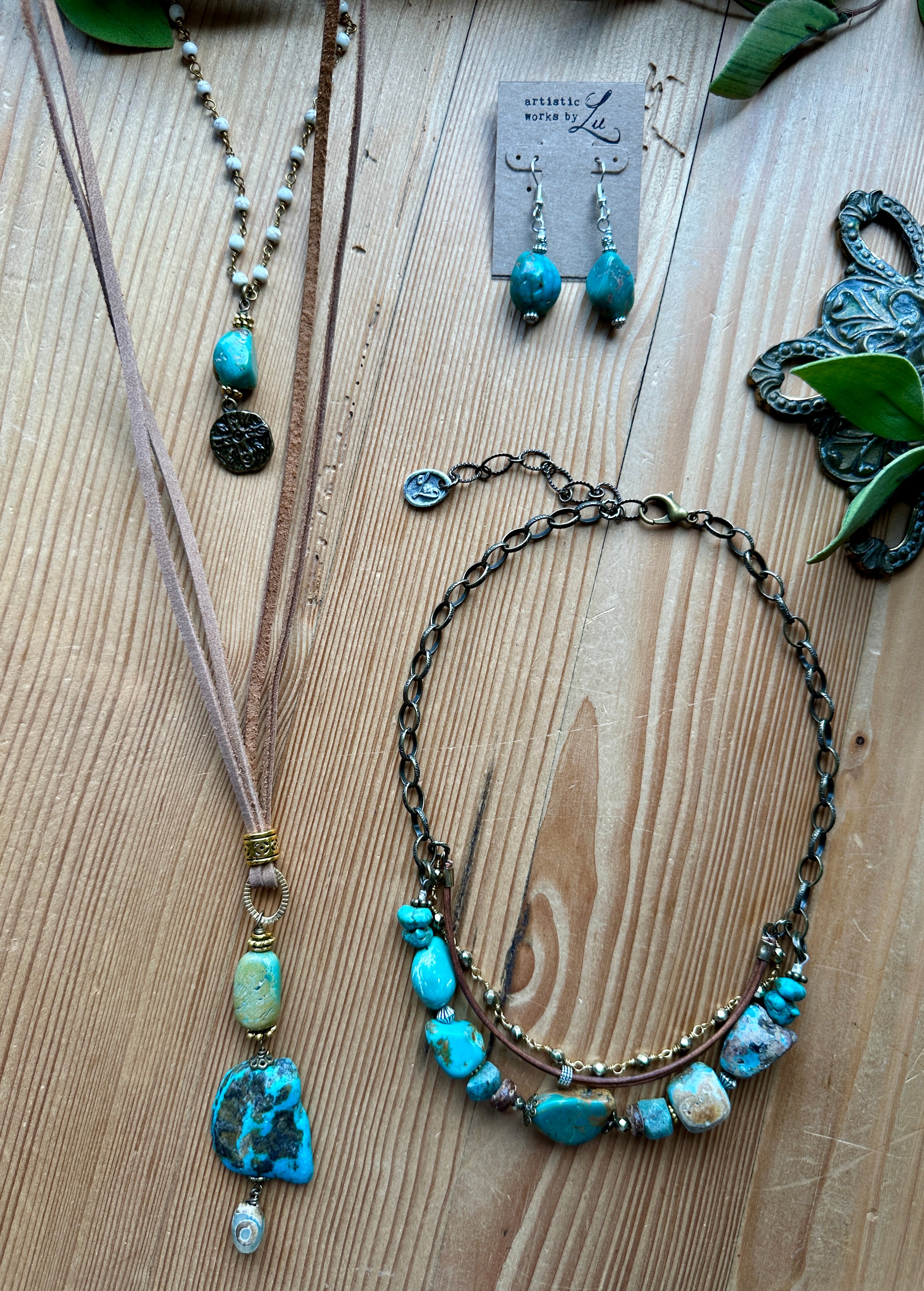 Handmade turquoise jewelry set including necklaces and earrings on a wooden surface