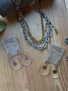 Gold and antique silver chains with delicate beads in necklace and earrings with tags on a wooden surface