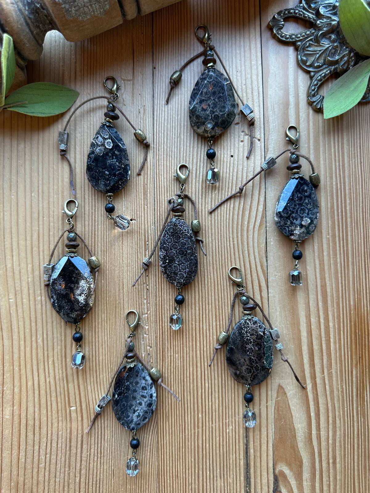 Sacred Ground Fossil Coral Pendant Charms with faceted dark fossil coral stones, pyrite, brown cord wrap, black bead, crystal drop, and brass lobster clasps