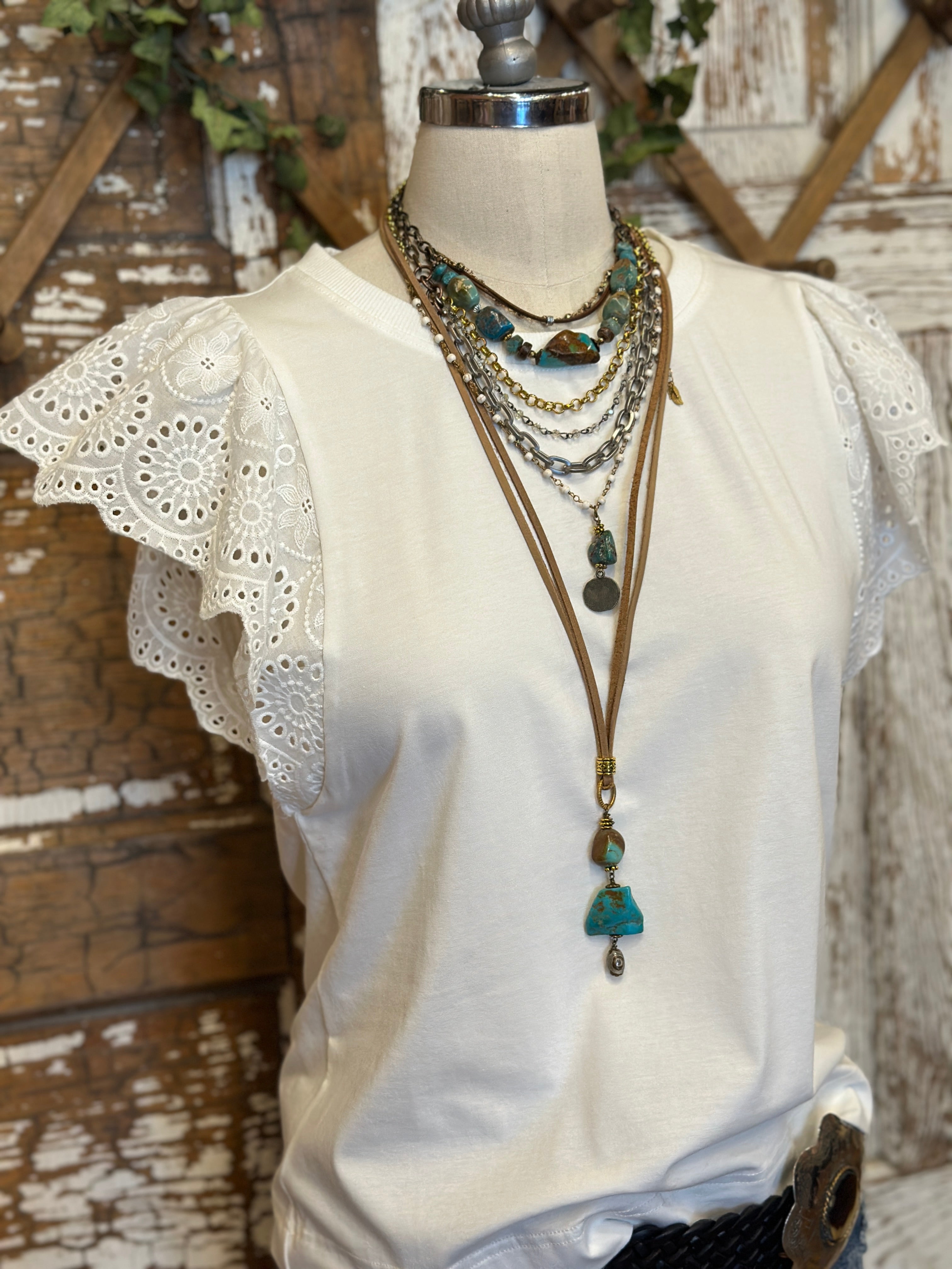 Mannequin wearing a white blouse with lace sleeves and layered handmade necklaces in Leavenworth, KS boutique setting