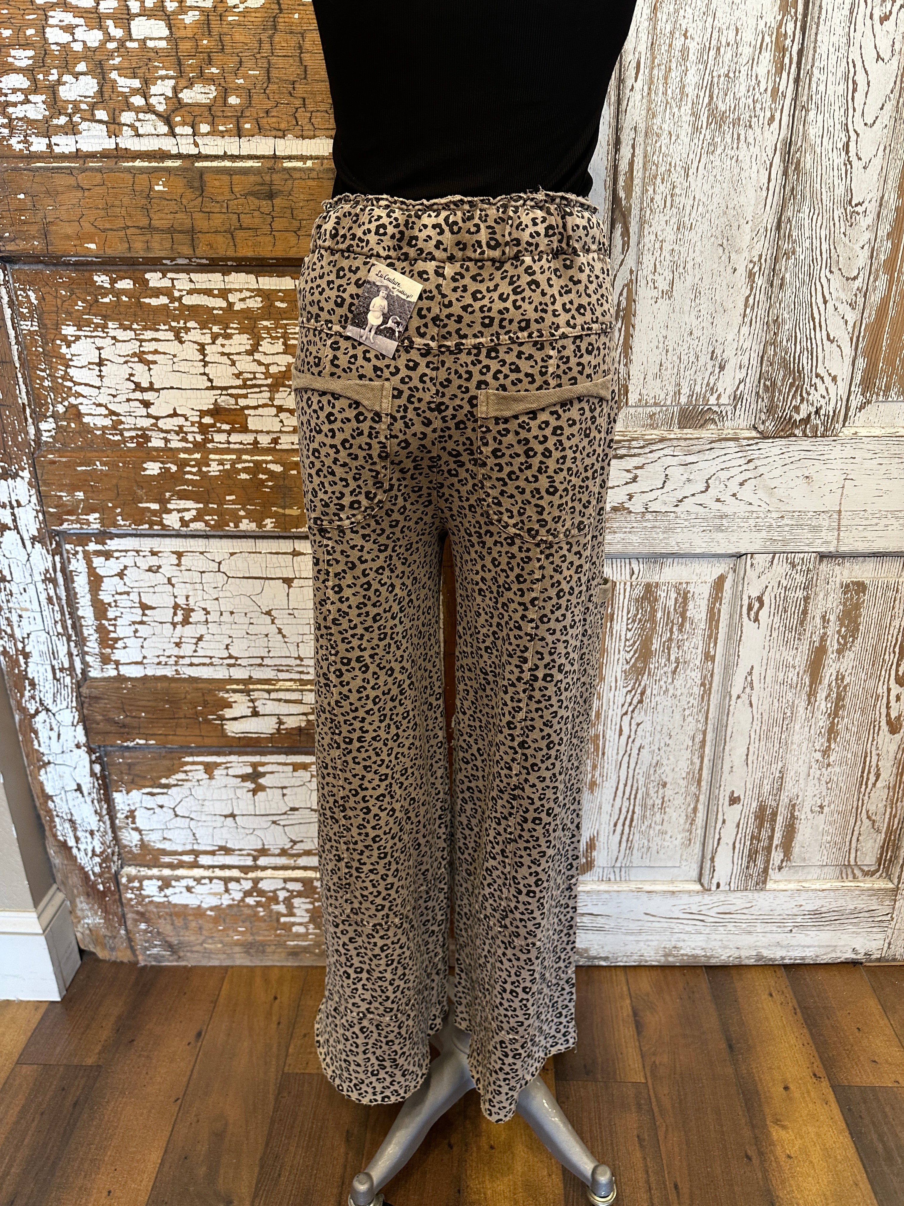 Lu wearing black flowy top and patterned leopard print leisurewear pants with handmade jewelry in a rustic boutique springfield, mo