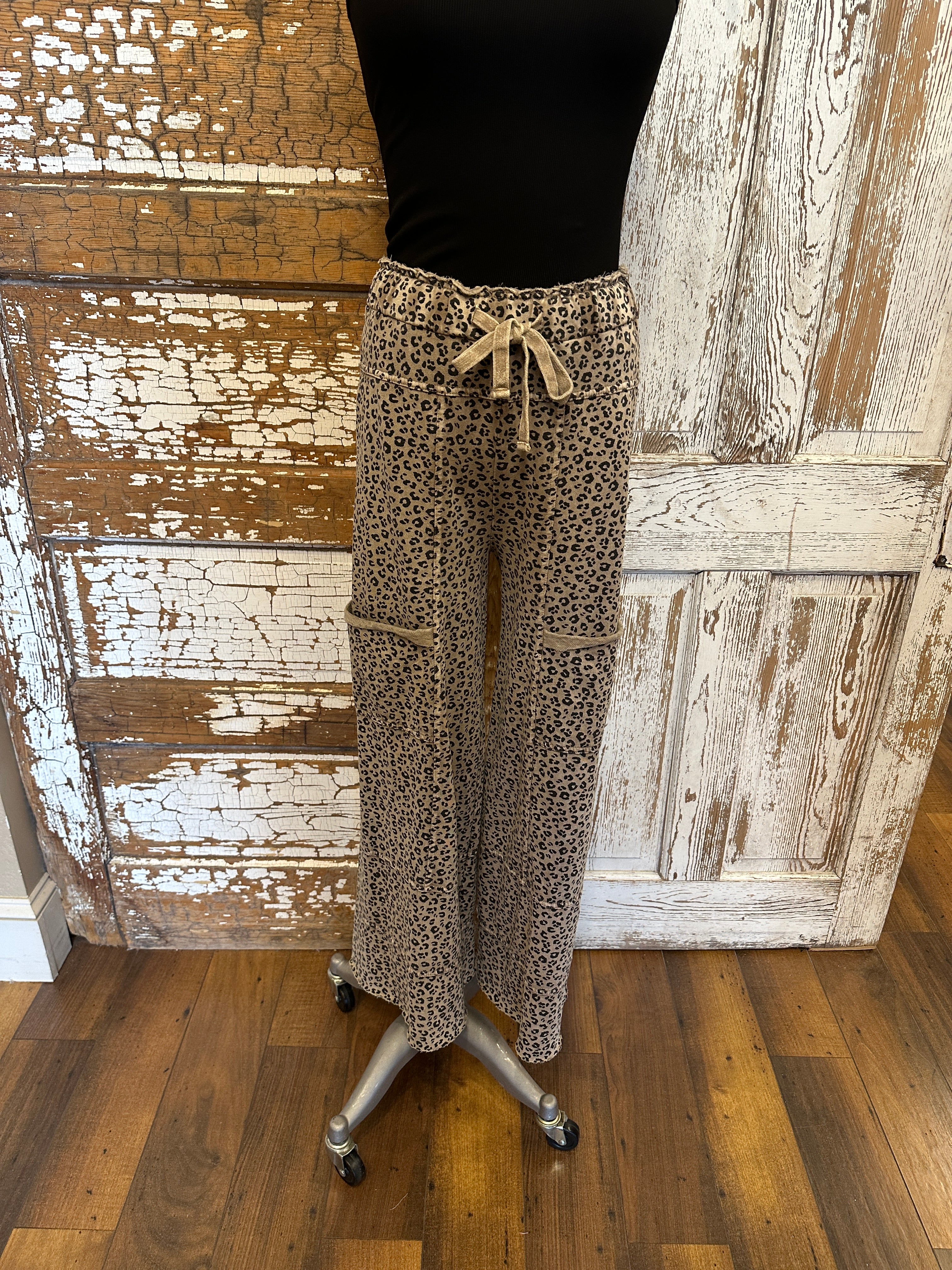 Lu wearing black flowy top and patterned leopard print leisurewear pants with handmade jewelry in a rustic boutique springfield, mo