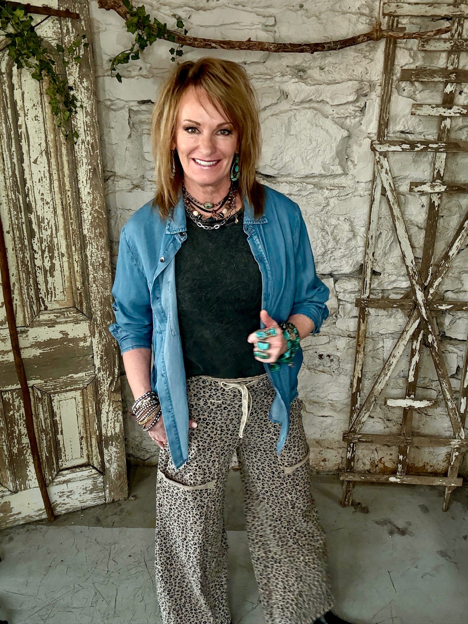 Mannequin wearing charcoal tank and denim shirt with patterned leopard print pants against a rustic boutique springfield, mo