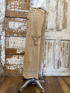 Person wearing a beige skirt with a wooden background