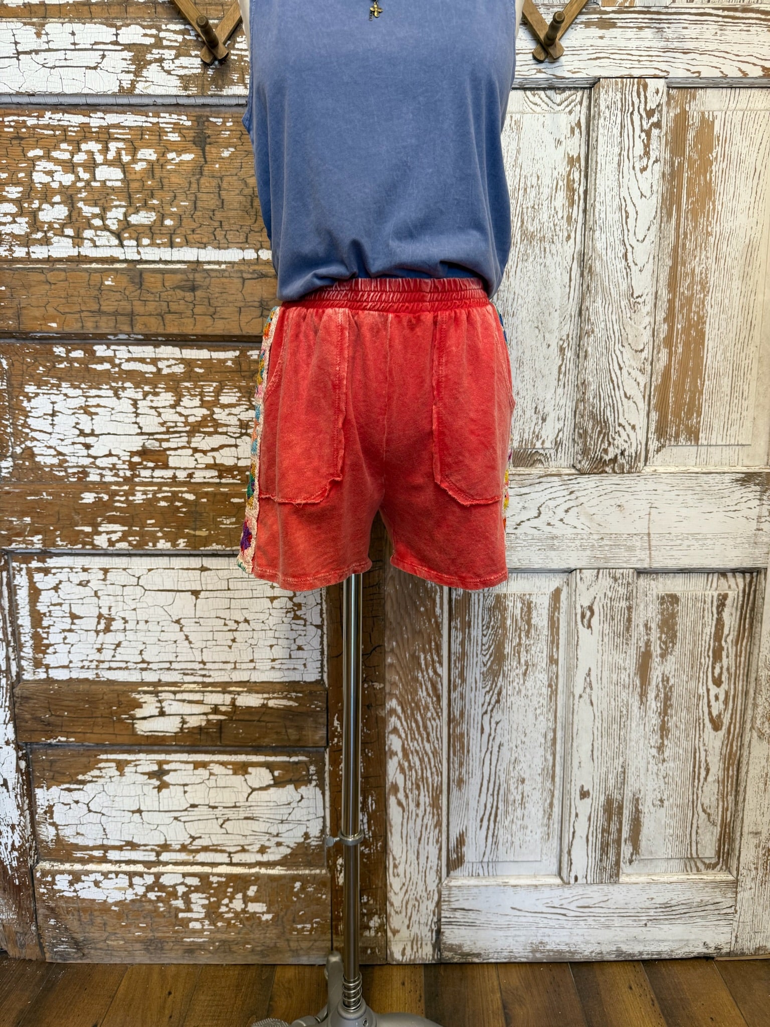Person wearing red shorts and a blue shirt against a wooden wall.