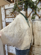 Lace-trimmed garment on a mannequin against a rustic wooden background