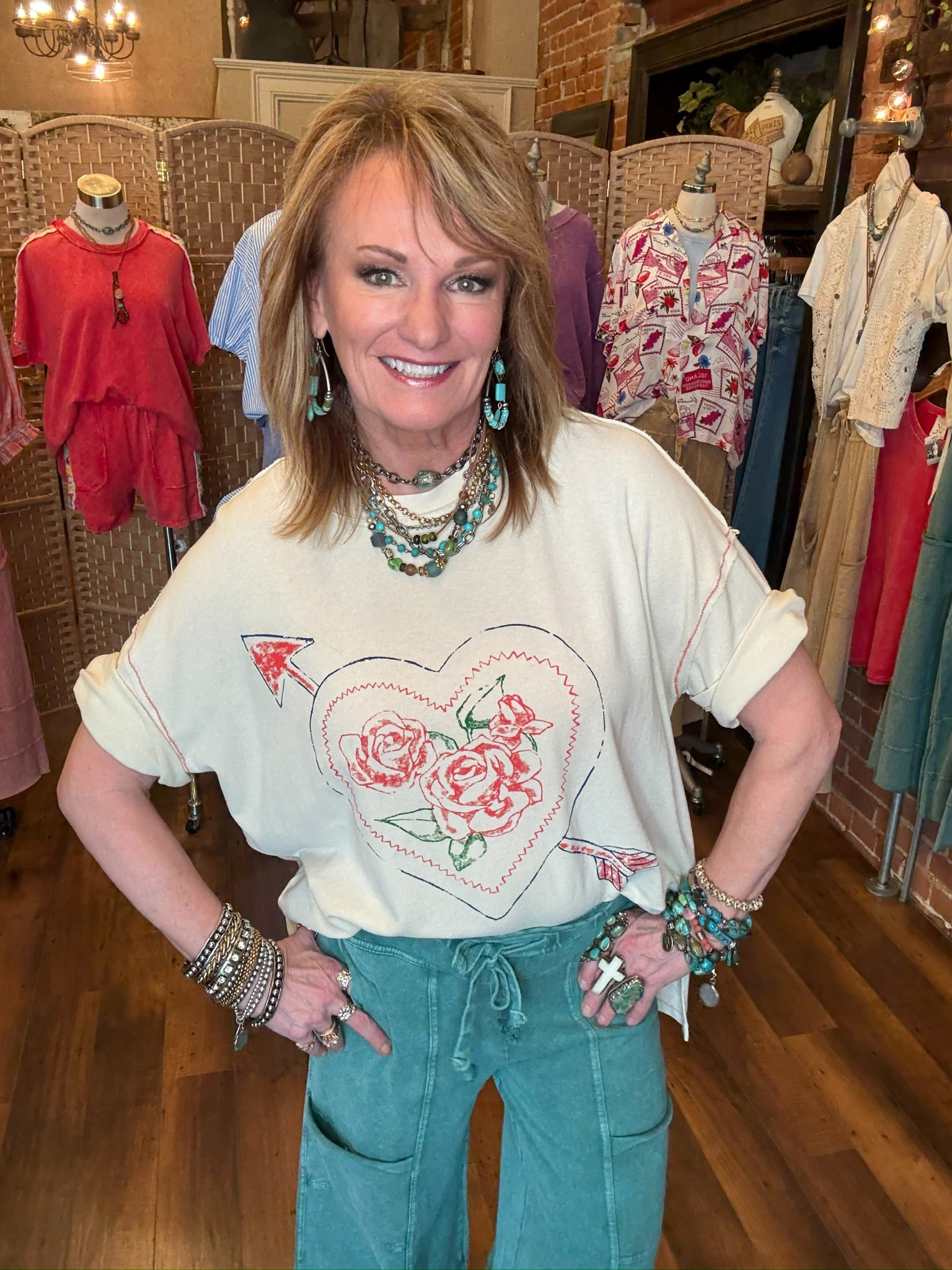 Lu wearing a graphic white t-shirt with a heart design and teal leisurewear in Springfield, MO boutique