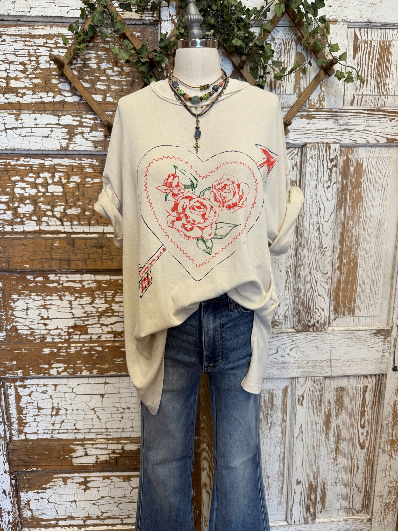 Mannequin wearing a cream graphic tee with floral heart design and jeans with handmade necklaces in Springfield, MO boutique