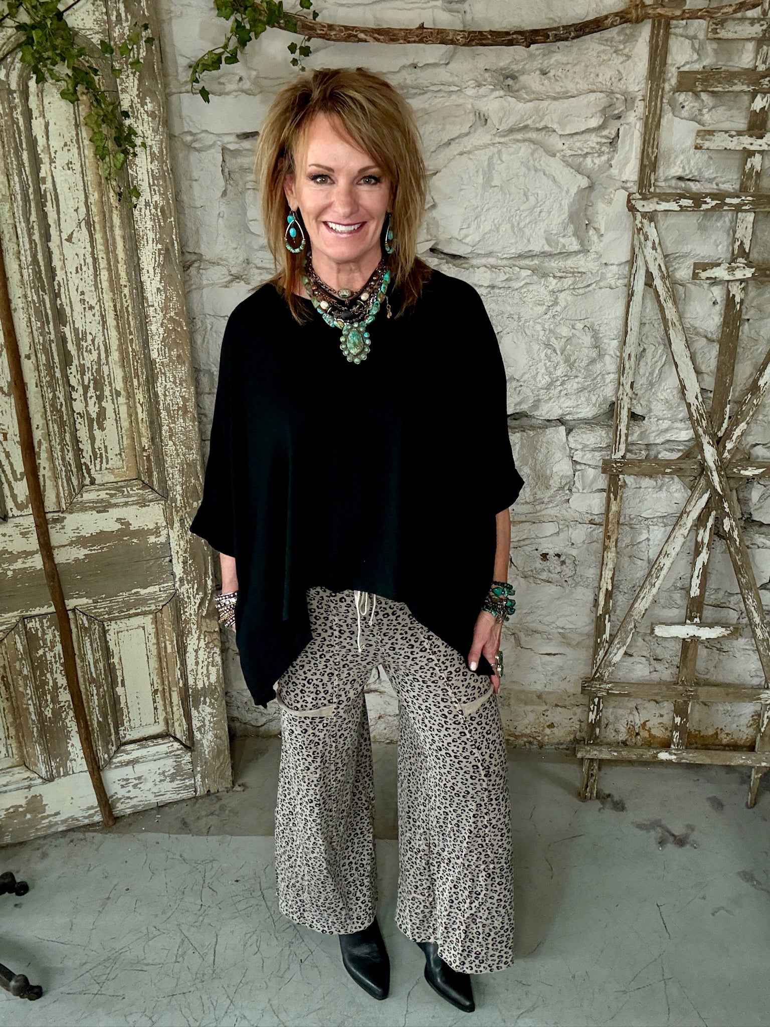 Lu wearing black flowy top and patterned leopard print pants against a rustic boutique springfield, mo