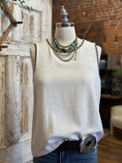 Mannequin wearing a white tank with stitching details and layered handmade necklaces in Leavenworth, KS boutique setting