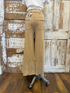 Beige wide-leg pants on a mannequin in front of a wooden door.
