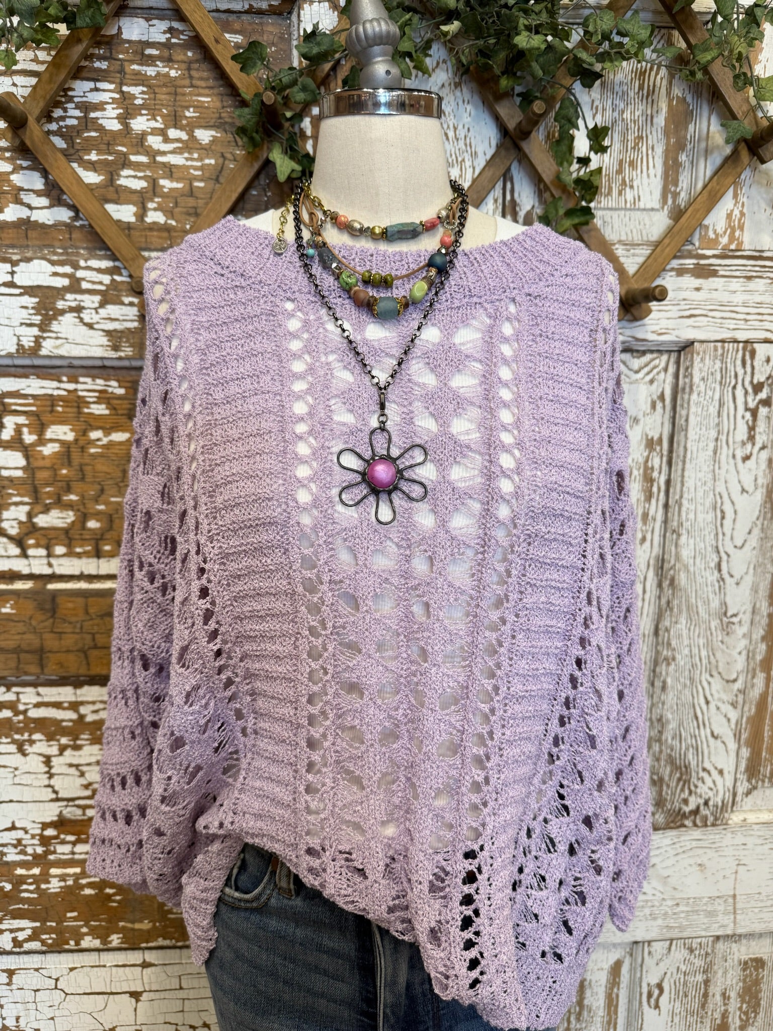 Lavender open knit sweater with handmade jewelry and jean pants on mannequin 
