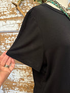 Black shirt held by a hand on a rustic wooden surface 