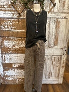 Mannequin wearing charcoal tank and patterned leopard print pants against a rustic boutique springfield, mo