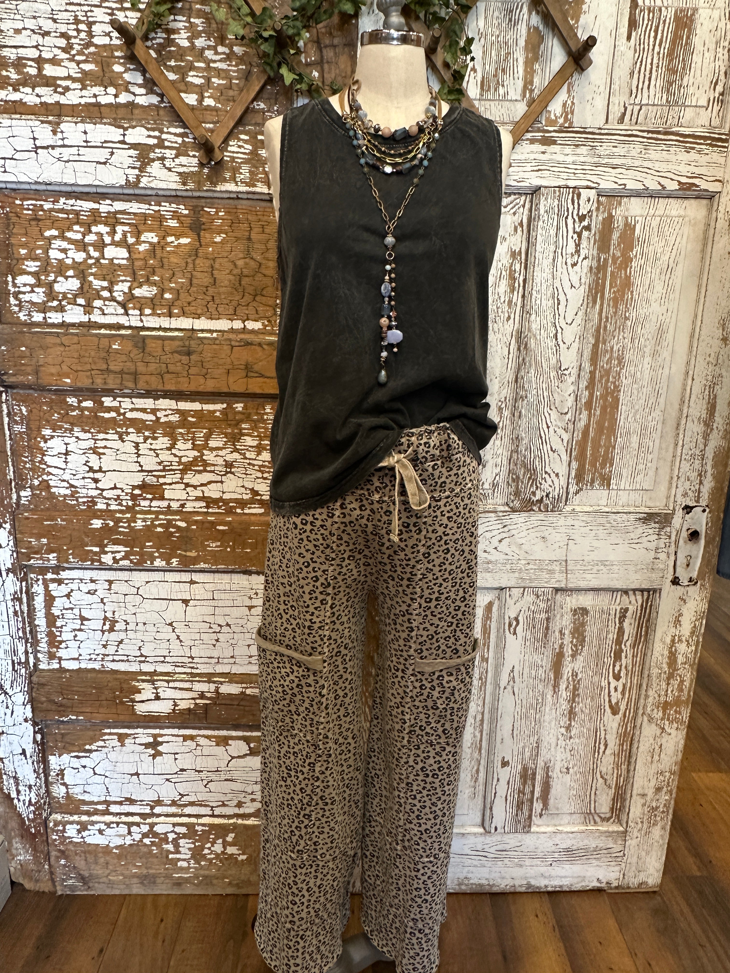 Mannequin wearing charcoal tank and patterned leopard print pants against a rustic boutique springfield, mo