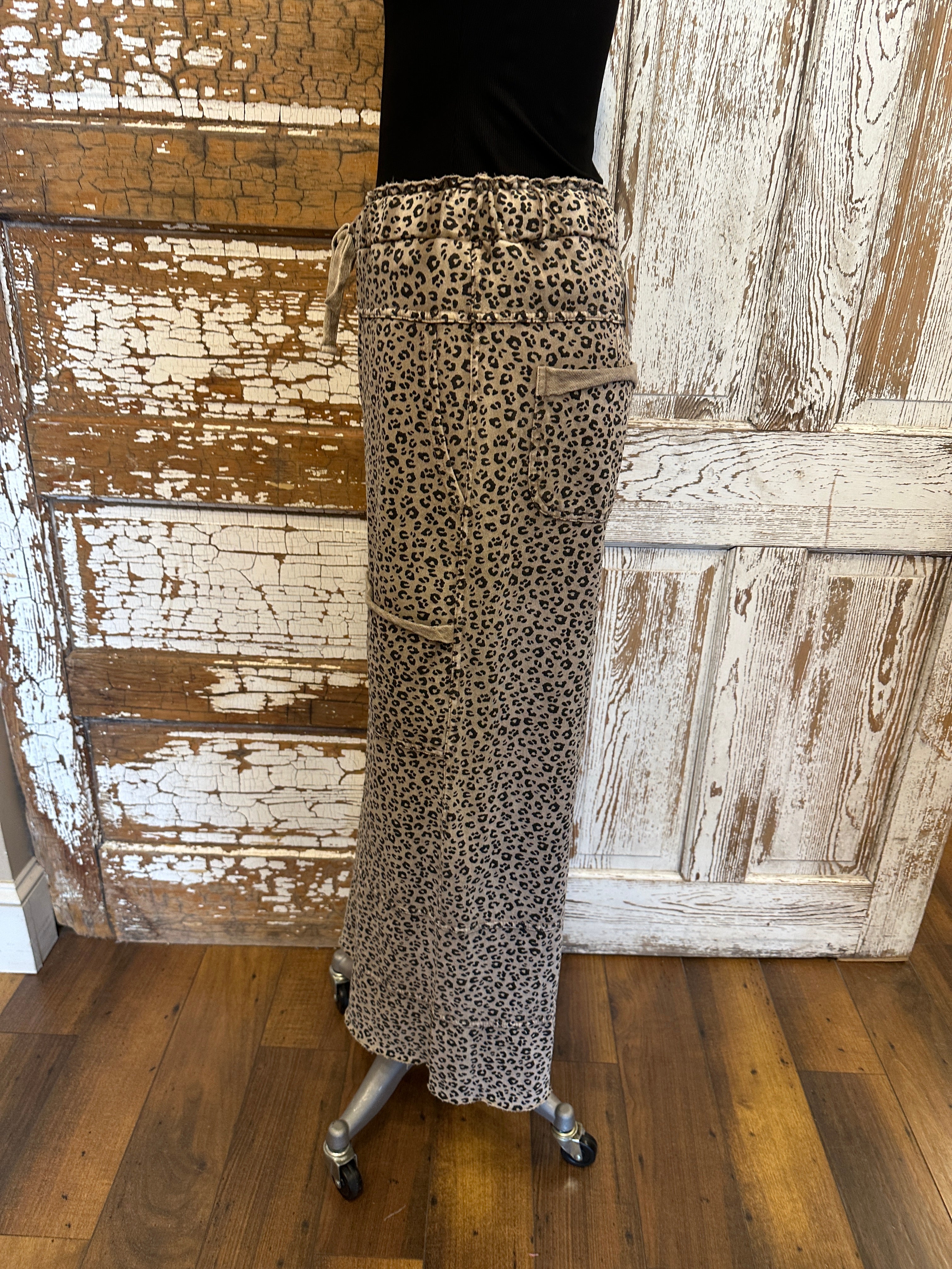 Lu wearing black flowy top and patterned leopard print leisurewear pants with handmade jewelry in a rustic boutique springfield, mo