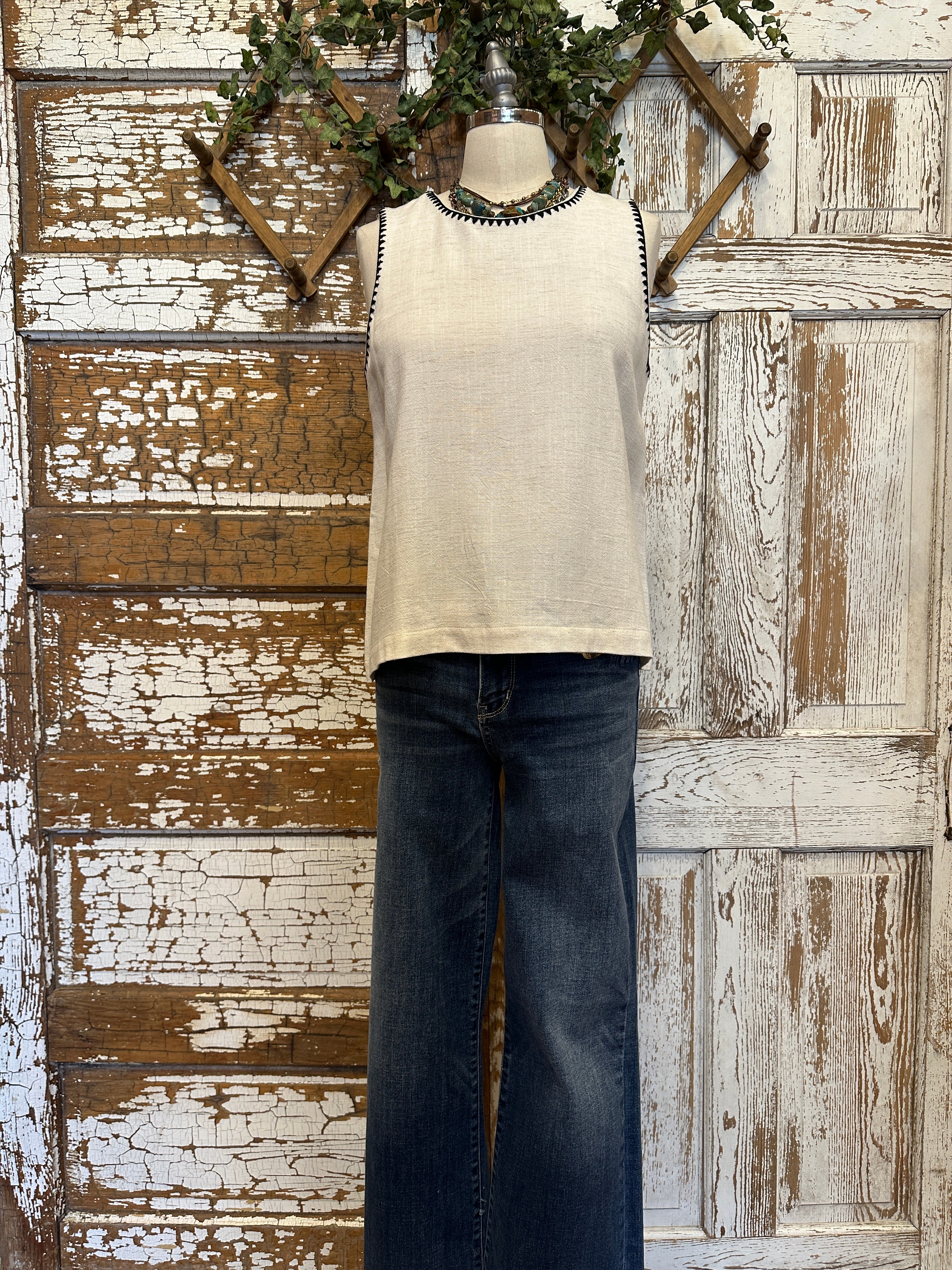 Mannequin wearing a Ivory Sleeveless Tank with Black Whipstitch Trim with layered handmade necklaces in Leavenworth, KS boutique setting