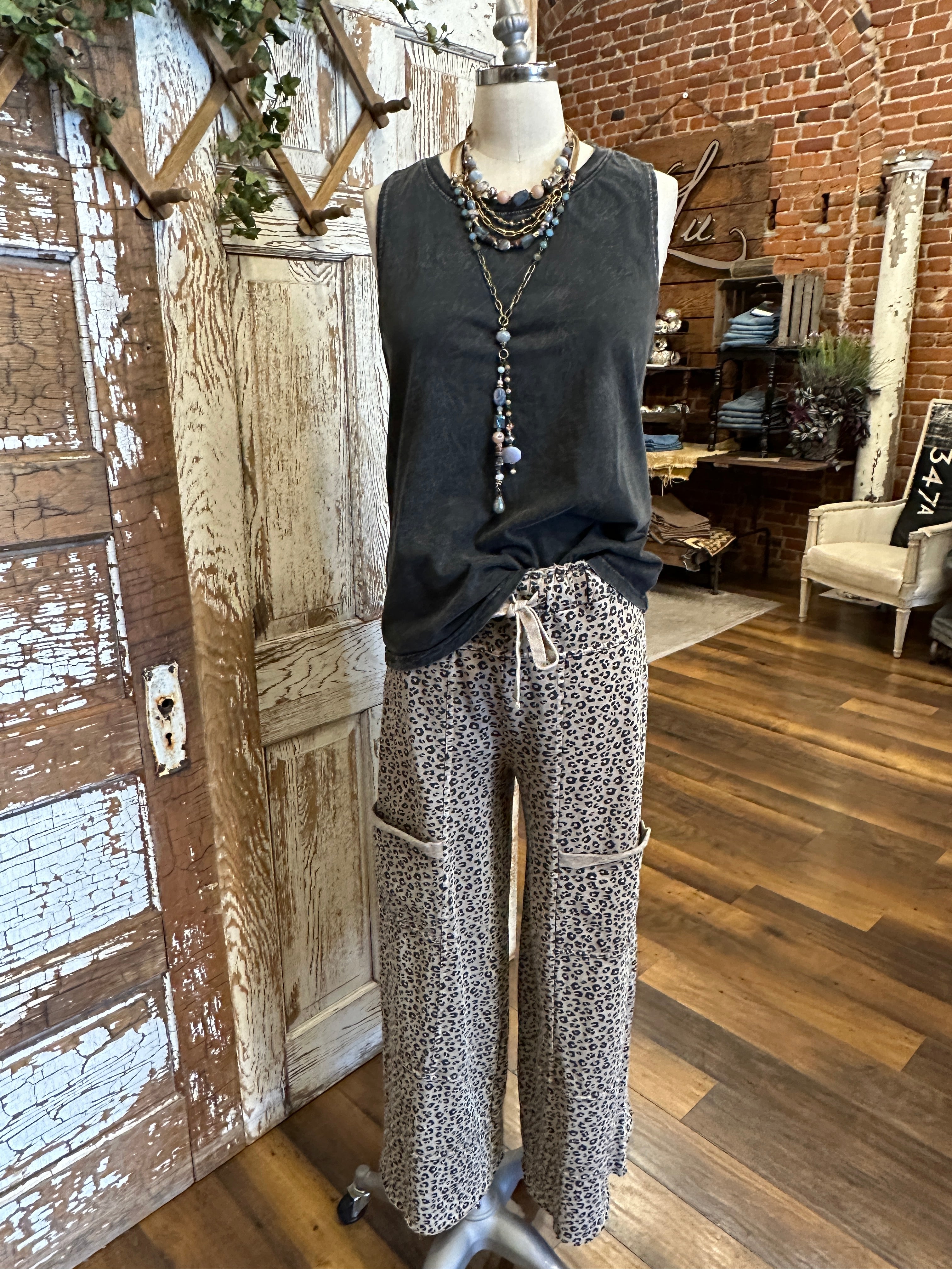Mannequin wearing charcoal tank and patterned leopard print pants against a rustic boutique springfield, mo