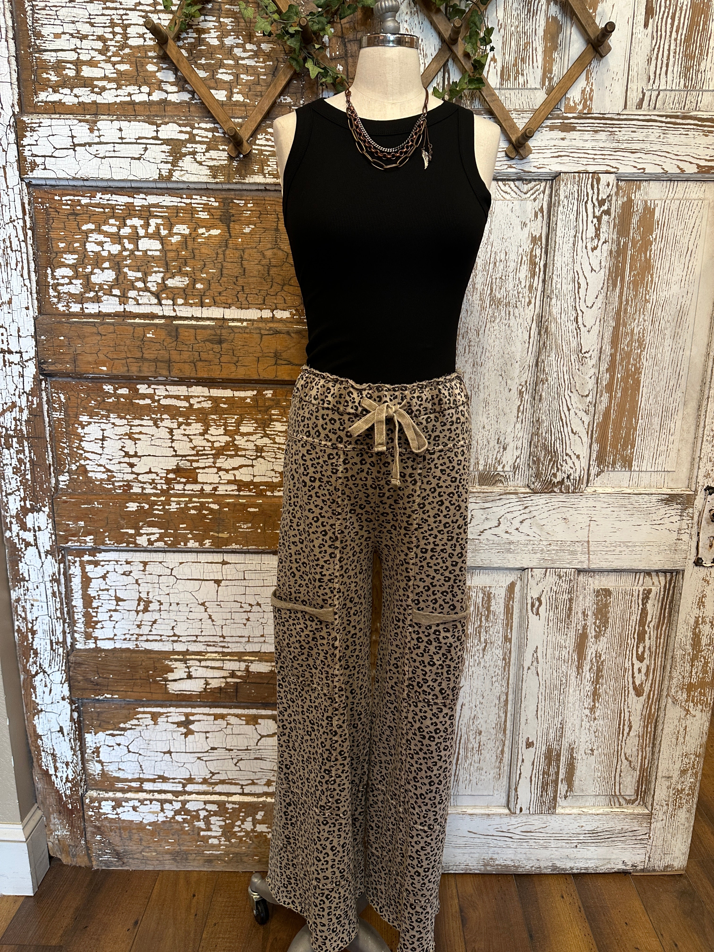 Lu wearing black flowy top and patterned leopard print leisurewear pants with handmade jewelry in a rustic boutique springfield, mo