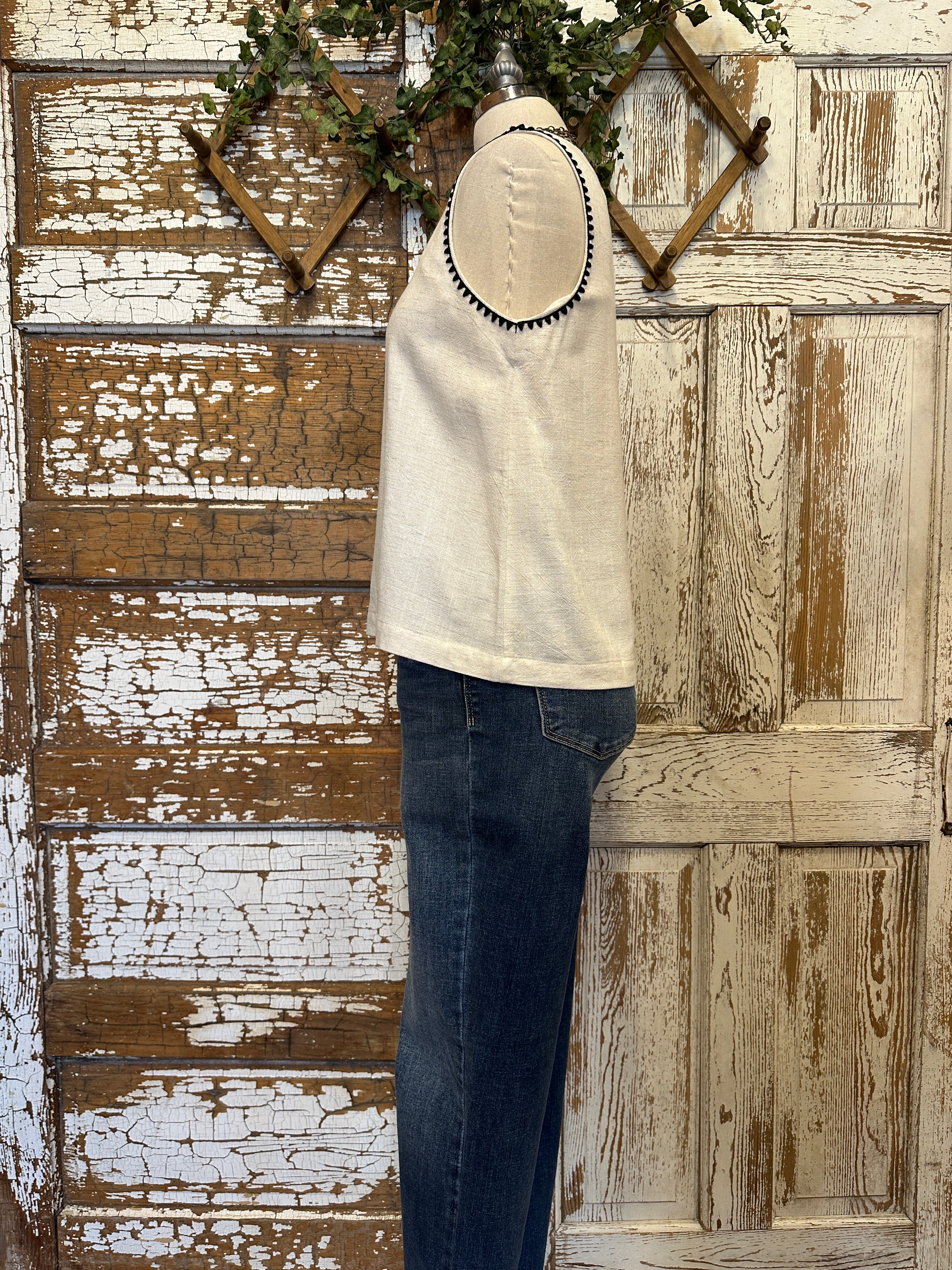Mannequin wearing a Ivory Sleeveless Tank with Black Whipstitch Trim with layered handmade necklaces in Leavenworth, KS boutique setting