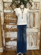 Mannequin wearing a white blouse with lace sleeves and layered handmade necklaces in Leavenworth, KS boutique setting