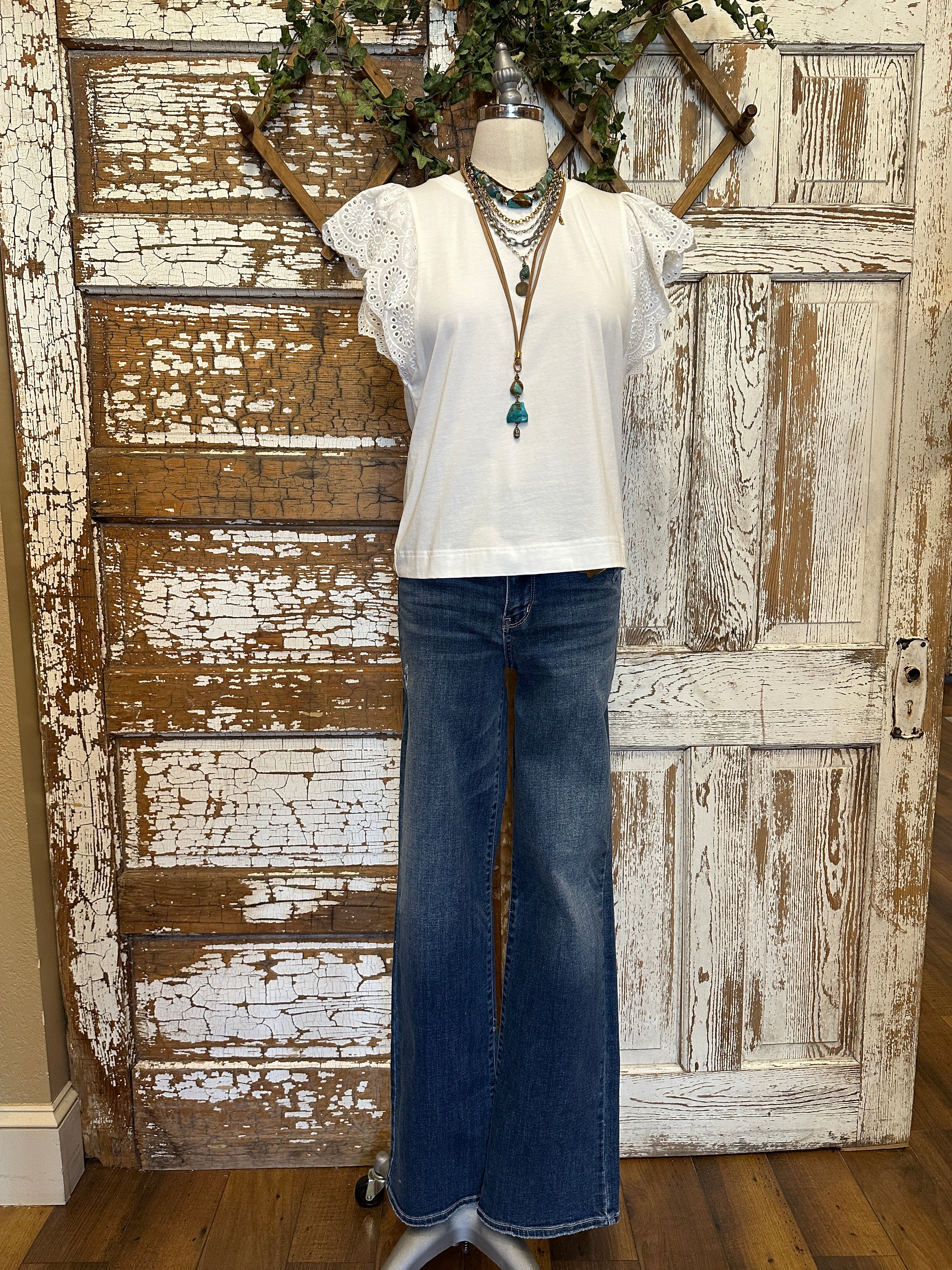Mannequin wearing a white blouse with lace sleeves and layered handmade necklaces in Leavenworth, KS boutique setting