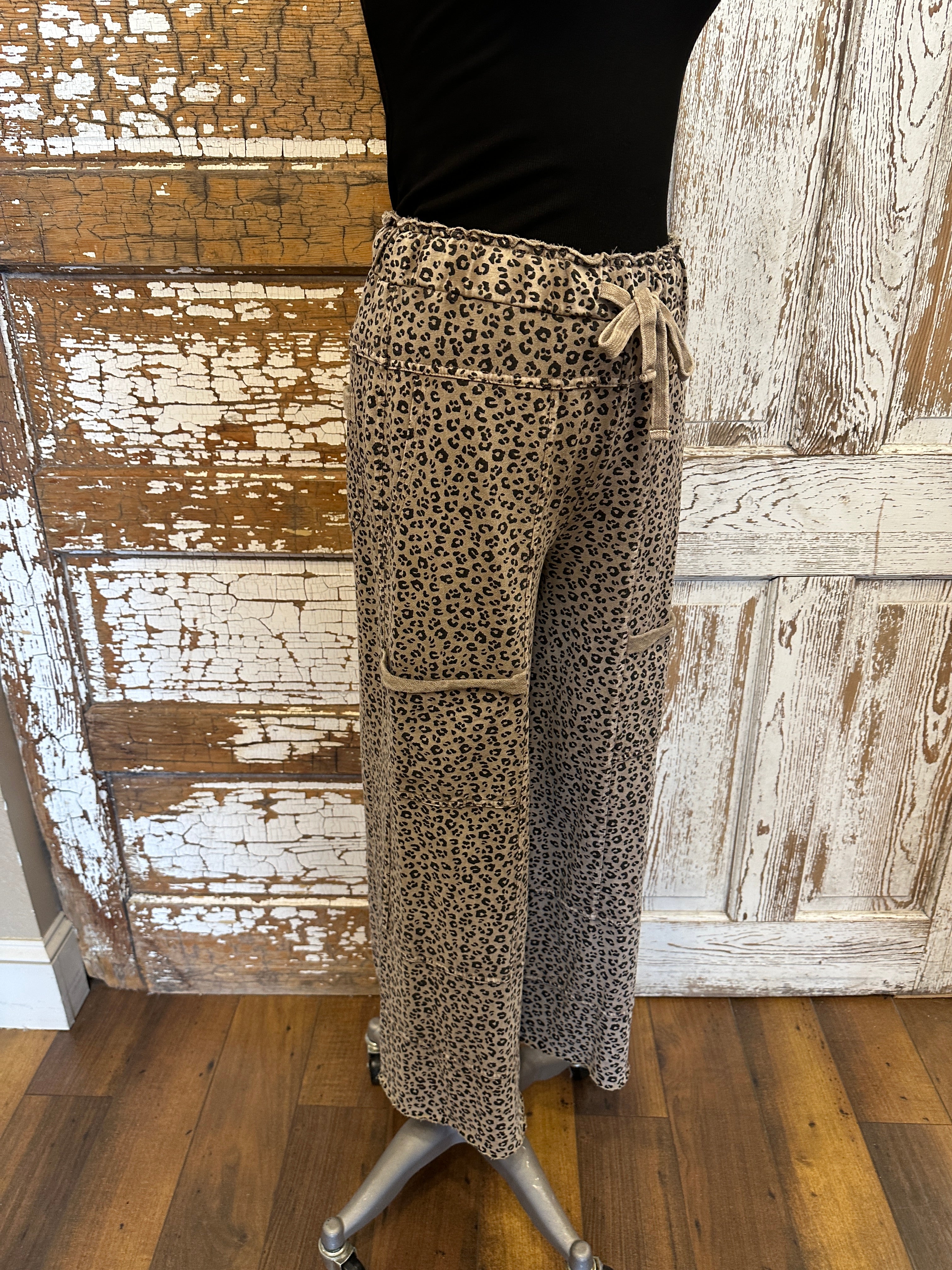 Lu wearing black flowy top and patterned leopard print leisurewear pants with handmade jewelry in a rustic boutique springfield, mo