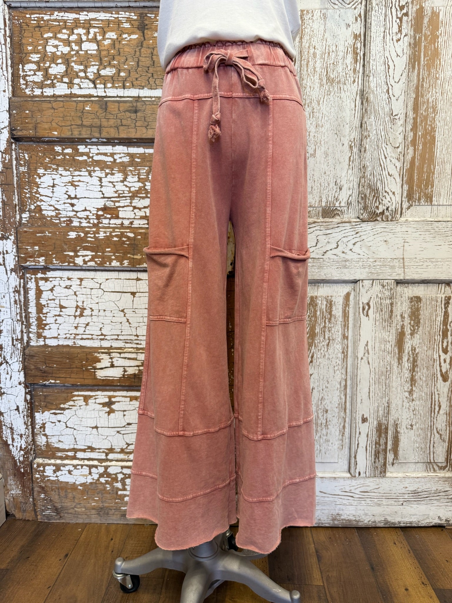 Pink wide-leg pants with drawstring waist on a wooden floor.