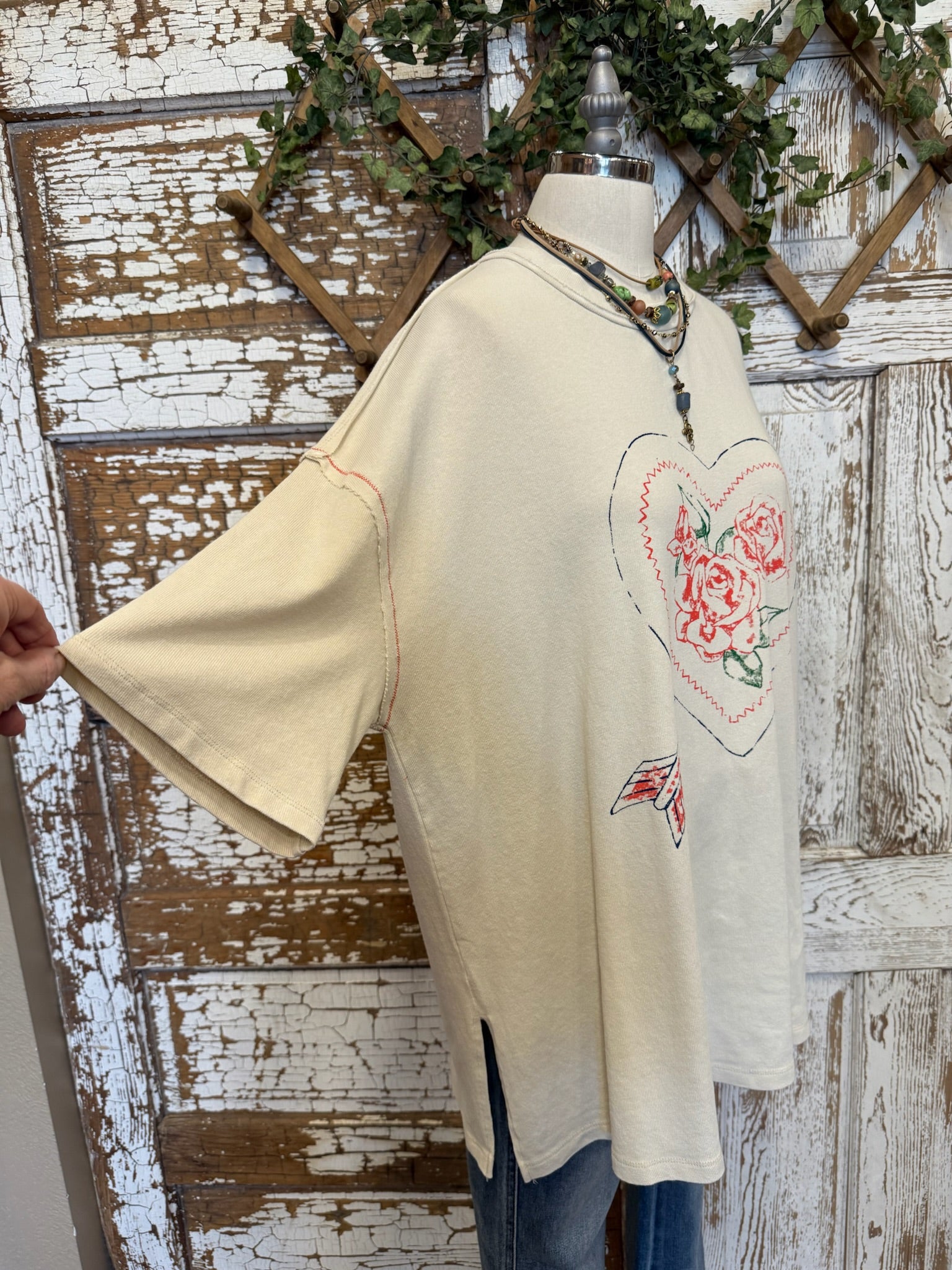 Mannequin wearing a cream graphic tee with floral heart design and jeans with handmade necklaces in Springfield, MO boutique